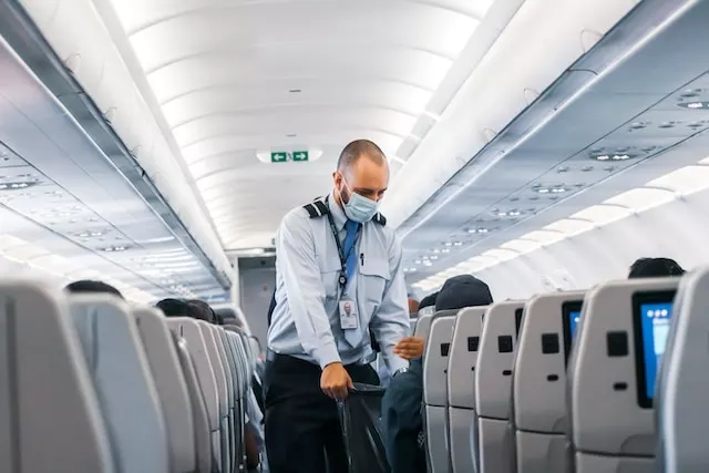 A man in a blue dress shirt is inside an airplane, about travel tips.